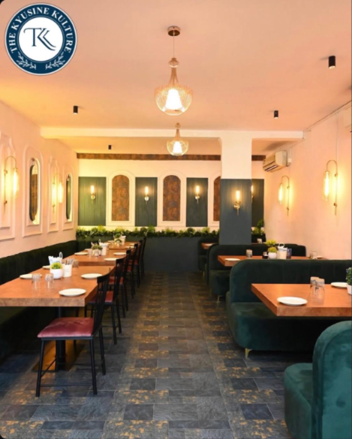 Dining room with green velvet booths, wall sconces and pendant lights